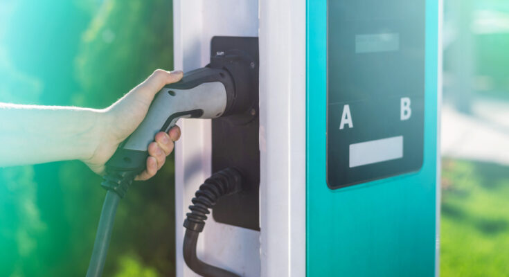 Man Unplugging Electric Charger From Dock Charge Station