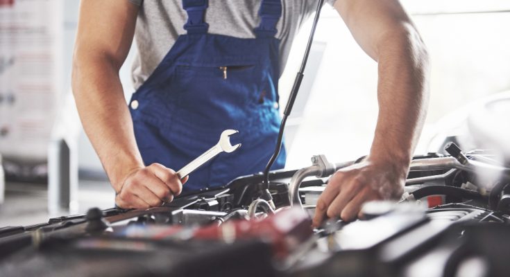 Muscular Car Service Worker Repairing Vehicle