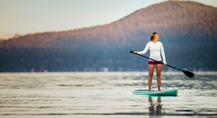 Young,woman,paddle,boarding,on,a,lake.